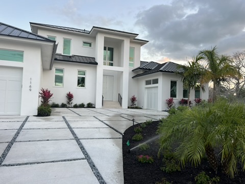 Finished two-story white home with a metal roof and landscaped drive