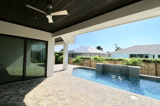 Covered lanai with wood ceiling overlooking a pool