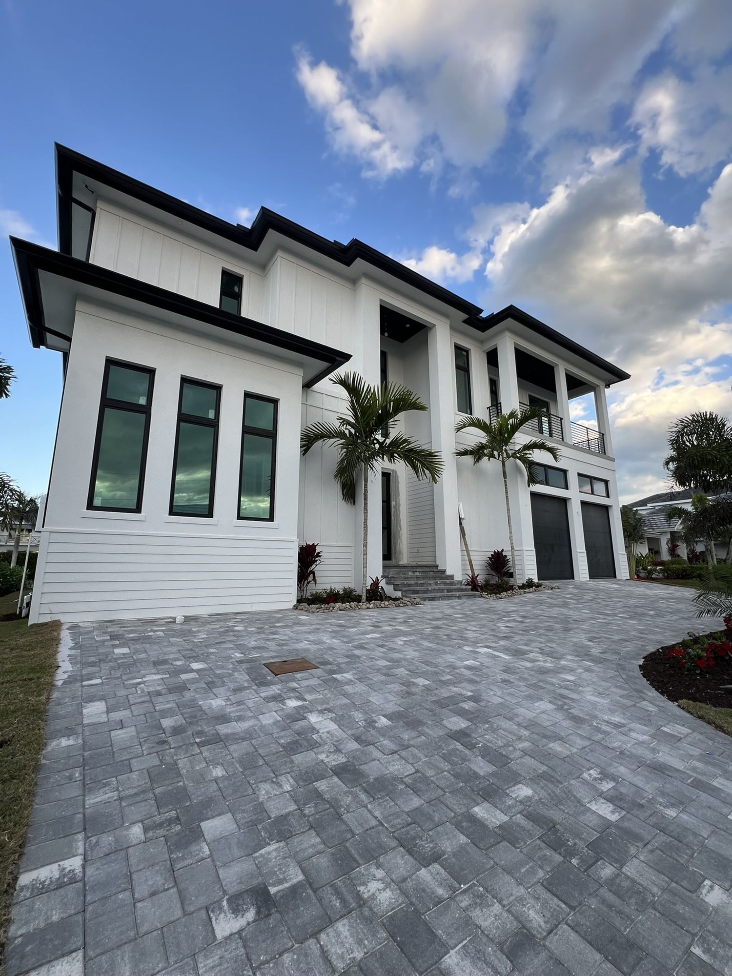 Orchid Court, a new two-story white home with dark trim and paver driveway on Marco Island